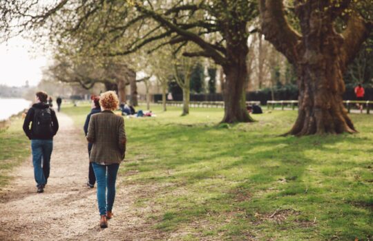 rear-view-people-walking-riverbank
